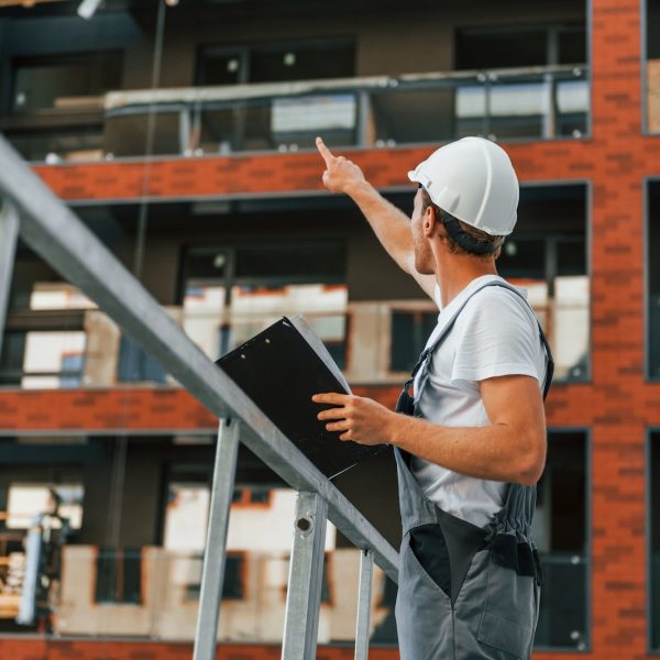 Manager of project. Young man working in uniform at construction at daytime